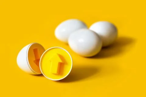 Plastic eggs with arrow form on yellow background. An educational sorter toy to Фото