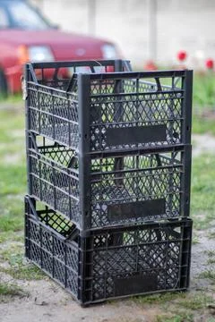 Plastic empty black boxes stacked together for plants or harvest. On a sunny  Stock Photos
