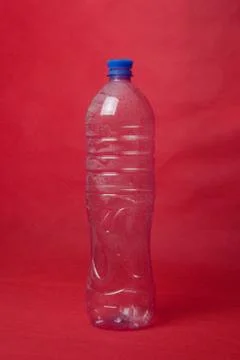 A plastic empty bottle on a red background with space for text. Concept of en Stock Photos
