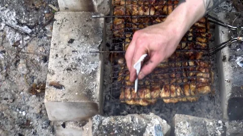 Plastic fork pierces fried yummy pieces of meat on the grill. Hand with a Video stock 75532740