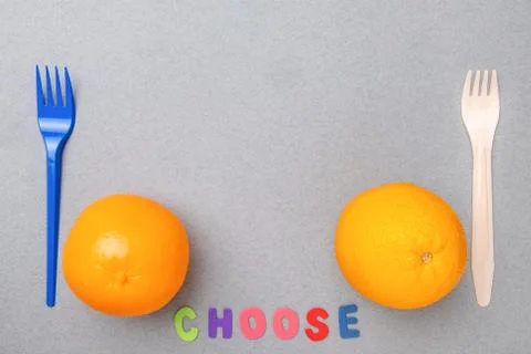 Plastic fork, plastic toy orange, wooden fork and natural orange. Flat lay. Stock Photos