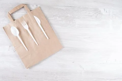 Plastic fork, spoon, knife on paper bag. Eco-friendly food packaging and cotton Stock Photos