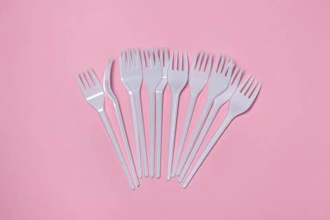 Plastic forks on a pink background. Disposable tableware.  Stock Photos