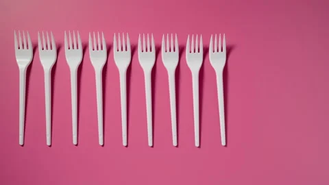 Plastic forks in a raw on a pink background. Stop motion. Vídeo Stock 133229004