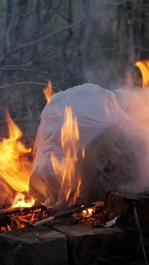 Plastic garbage bag burning in a bonfire releasing toxic smoke and fumes Stock Footage 344798881