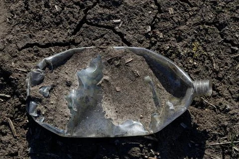 Plastic garbage, bottle lie on dry ground. Ecological disaster, problem Stock Photos