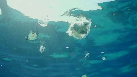 Plastic garbage drifts under surface of sea in sunrays, slow motion Stock Footage 237522937