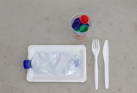 Plastic garbage on a plate, next to fork, spoon and cup filled with plastic 库存照片