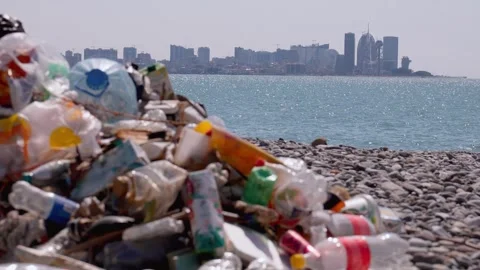 Plastic garbage polluting a beach with a city skyline view Vidéo 337883811