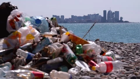 Plastic garbage polluting a beach near a modern city Video stock 337645508