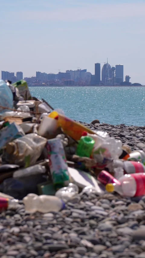 Plastic garbage polluting a beach near a modern city 스톡 동영상 337645831