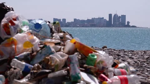 Plastic garbage polluting a beach near a modern city 스톡 동영상 338162571