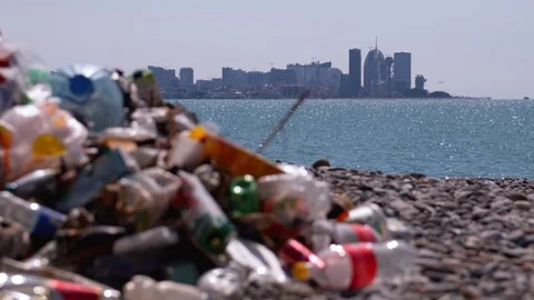 Plastic garbage polluting a beautiful ocean beach Stock Footage 338408837