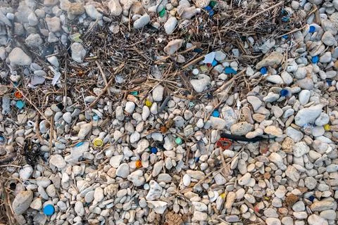 Plastic garbage on the seashore. Top view of a polluted beach. Stones and shells Stock Photos