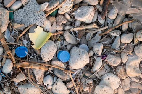 Plastic garbage on the seashore. Top view of a polluted beach. Stones and shells Stock Photos