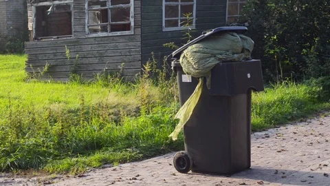 Plastic hay wrap in garbage container in front of a farm shed ruin Stock Footage