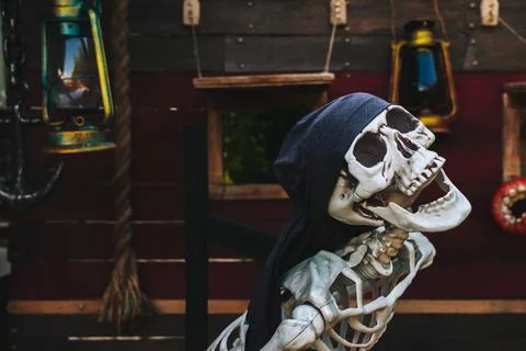 Plastic human skeleton prop wearing black bandanna against dark vintage woo.. Stock Photos