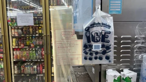 Plastic ice bag hanging from ice machine inside 7-11 store with beverages fridge Stock Footage 249587357
