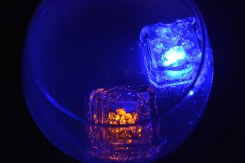 Plastic ice cubes with LEDs float in drinks of red, blue, green light. Foto stock