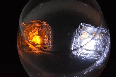 Plastic ice cubes with LEDs float in drinks of red, blue, green light. Stock-Fotos