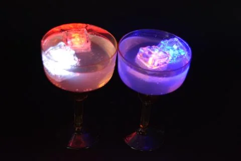 Plastic ice cubes with LEDs float in drinks of red, blue, green light. Stock Photos