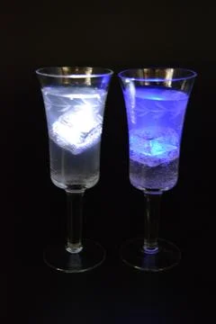 Plastic ice cubes with LEDs float in drinks of red, blue, green light. Stock Photos