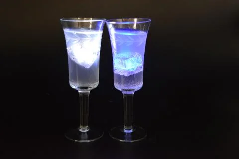 Plastic ice cubes with LEDs float in drinks of red, blue, green light. Stock Photos