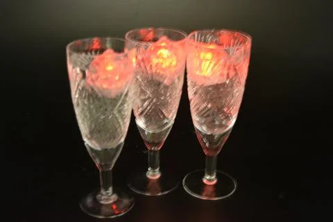 Plastic ice cubes with LEDs float in drinks of red, blue, green light. Stock Photos