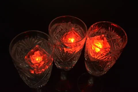 Plastic ice cubes with LEDs float in drinks of red, blue, green light. Stock Photos
