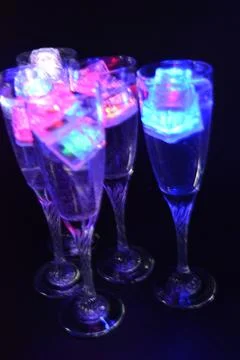 Plastic ice cubes with LEDs float in drinks of red, blue, green light. Stock Photos