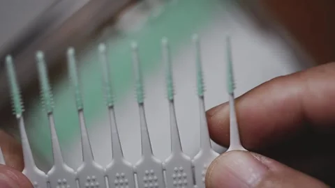 Plastic interdental brush strip snapping and detaching from pack close-up Stock Footage 345506362