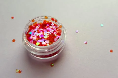 Plastic jar with red sequins on grey paper table Photos