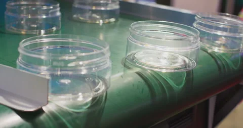 Plastic jars falling off conveyor belt in production line Stock Footage 329182300