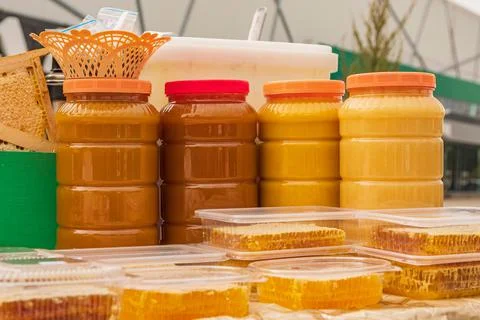 Plastic jars filled with multi-colored ripe bee honey. There is trade at autumn Stock Photos