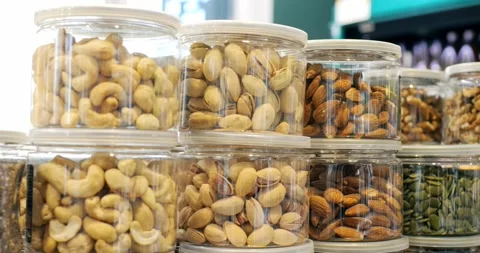Plastic jars filled with various nuts, including cashews, pistachios, and Stock Footage 309045912