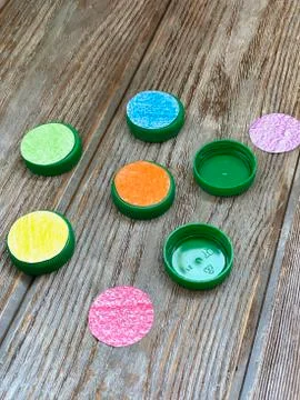 Plastic lids are processed with colored paper for children's play. Stock Photos