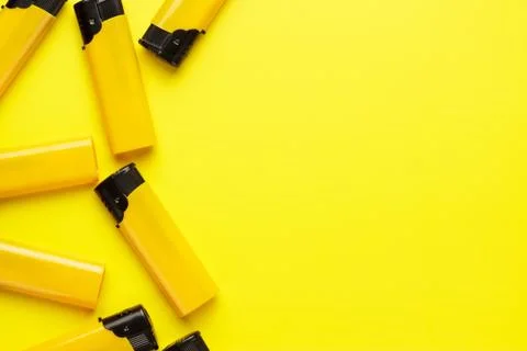 Plastic lighters on yellow background Stock Photos