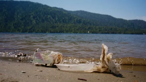 Plastic litter lies washed ashore by gentle waves Stock Footage 335813761