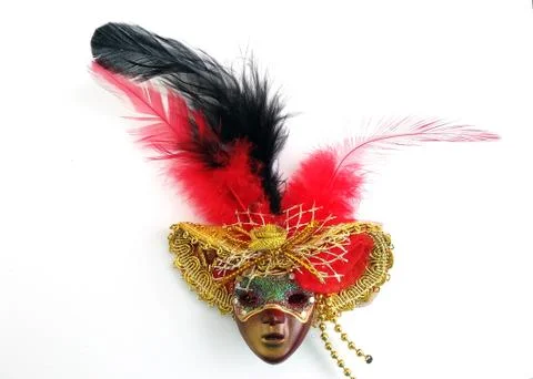Plastic mask in a hat with feathers on a white background top view. Stock Photos