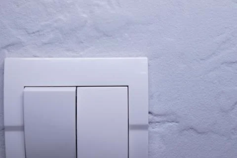 Plastic mechanical white light switch, installed on a light gray wall Stock Photos
