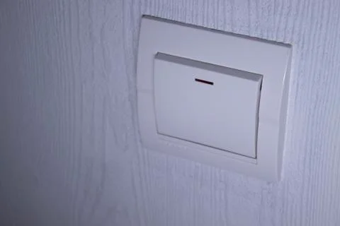 Plastic mechanical white light switch, installed on a light gray wall Stock Photos