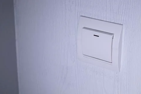 Plastic mechanical white light switch, installed on a light gray wall Stock Photos