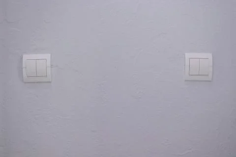 Plastic mechanical white light switch, installed on a light gray wall Stock Photos