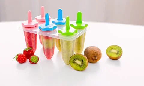 A plastic mold with multi-colored homemade kiwi and strawberry ice cream stands Stock Photos