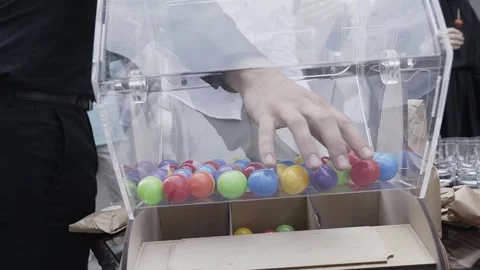 Plastic multi-colored balls are mixed in the lottery machine and people take out 库存影片 306144906