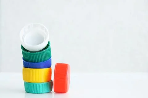 Plastic multi-colored bottle caps on a white background. Close-up. Stock Photos