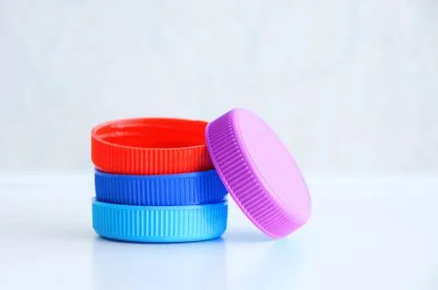 Plastic multi-colored bottle caps on a gray background. Close-up. Stock Photos