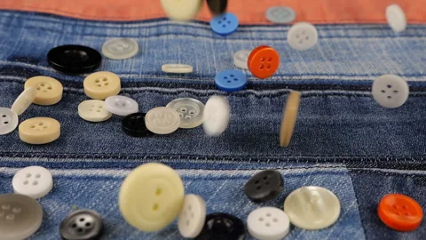 Plastic multi-colored buttons fall on denim. Slow motion. Video stock 229486162