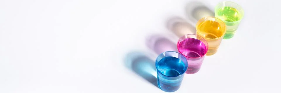 Plastic multi-colored glasses with liquid on a white background with highligh Stock Photos