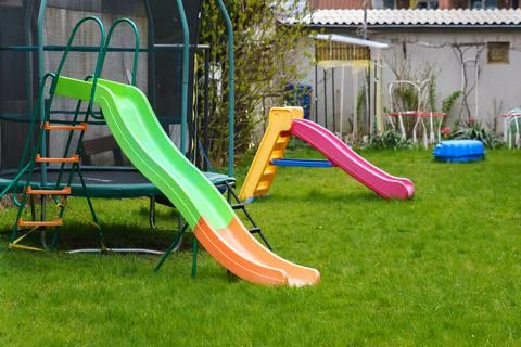 Plastic multi-colored slides on the playground. Green grass on the lawn. Stock Photos